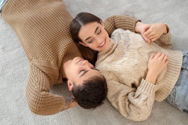 Sevgi dolu genç bir çift evde yerde yatıyor, manzarası harika.