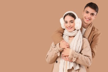 Kışın giyinmiş, bej arka planda kucaklaşan mutlu çifti seviyorum.