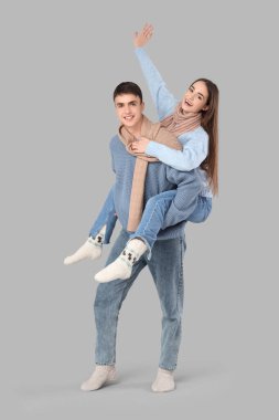 Kışın giyinmiş, gri arka planda eğlenen mutlu çifti seviyorum.