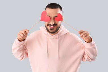 Gri arka planda kağıt kalpli yakışıklı genç adam.