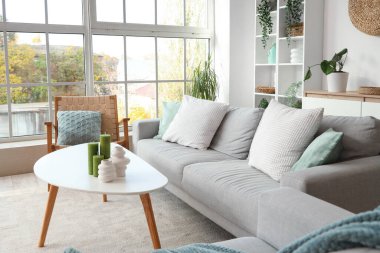 Koltukları, koltuğu ve yeşil bitkileri olan aydınlık oturma odasının içinde.