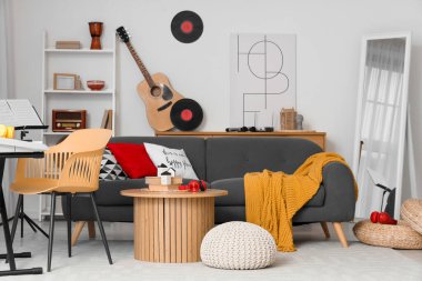 Oturma odasının içinde kanepe, masa ve müzik aletleri var.