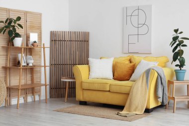 Sarı kanepe ve ahşap perdelerle aydınlık oturma odasının içinde.