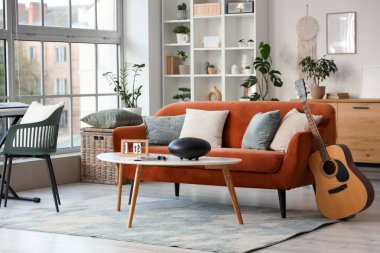 Oturma odasının içinde kanepe, masa ve müzik aletleri var.