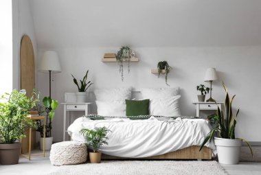 Rahat yataklı, komodinli ve çiçekli, aydınlık yatak odasının içi.