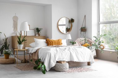 Konforlu yatağı ve çiçekleri olan hafif yatak odasının içi.