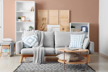 Gri kanepe, masa ve ahşap perdeli oturma odasının içi.