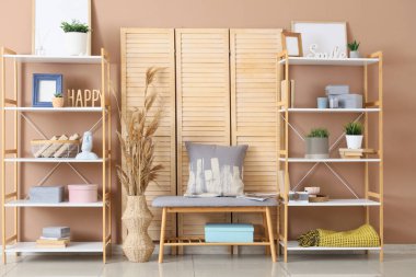 Odanın içi yumuşak bank, raf üniteleri ve ahşap katlanır ekran.