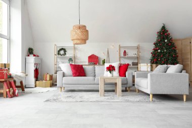 Masasında kanepeler, raf üniteleri ve Noel çiçekleri olan aydınlık oturma odasının içi.