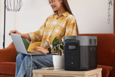 Taşınabilir elektrik santrali. Evinde dizüstü bilgisayar kullanan bir kadına karşı. Yakın plan.