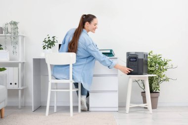 Genç bir kadın ofisteki taşınabilir elektrik santralini açıyor.