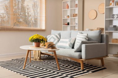 Masada kanepe, kitap ve kasımpatı çiçekleri olan oturma odası.