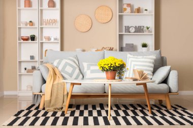 Masada kanepe, kitap ve kasımpatı çiçekleri olan oturma odası.