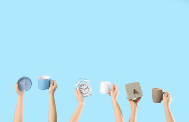 Çalar saatli kadın eller ve mavi arka planda bir fincan kahve. Günaydın konsept.