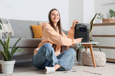 Genç bir kadın evdeki taşınabilir elektrik santralini açıyor.