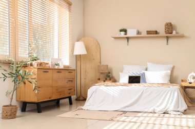 Yatak odasının içinde dizüstü bilgisayar, masa ve çekmeceler var.