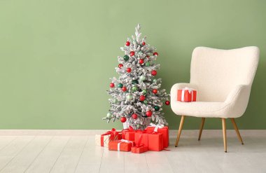 Koltuk ve Noel ağacı, yeşil duvarın yanında hediyeler.