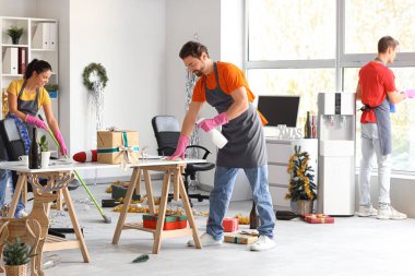 Yeni yıl partisinden sonra ofisi temizleyen genç hademe takımı.