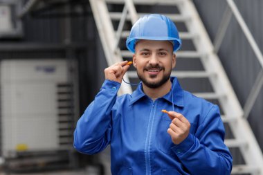 Male builder with earplugs outdoors clipart