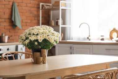 Mumlar ve beyaz kasımpatılar mutfaktaki masada.