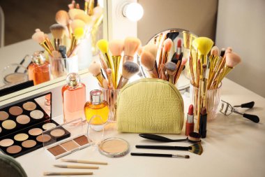 Kozmetik çanta, parfüm şişeleri, makyaj malzemeleri ve aksesuarlar odadaki tuvalet masasında.