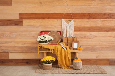 Kasımpatı çiçekli bank, bavullar, ekose ve balkabakları odasındaki tahta duvarın yanında.