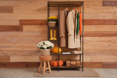 Koridorun içinde kasımpatı çiçekleri, palto askılığı ve balkabakları var.