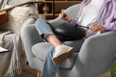 Evdeki koltukta glukofon çalan güzel, genç bayan besteci.