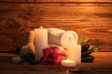 Koyu ahşap arka planda yanan mumlar ve okaliptüs dallarıyla güzel bir spa kompozisyonu.
