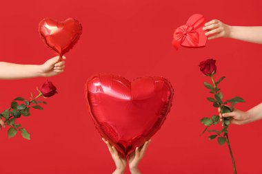 Hediye kutusu olan kadın elleri, kalp şeklinde balonlar ve kırmızı arka planda gül çiçekleri. Sevgililer Günü kutlaması