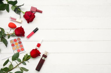 Makyaj ürünleri, oje, parfüm şişesi ve beyaz ahşap arka planda kırmızı gül çiçekleri.