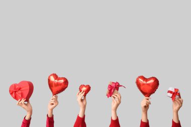 Hediye kutuları ve beyaz arka planda kalp şeklinde hava balonları olan kadın elleri. Sevgililer Günü kutlaması