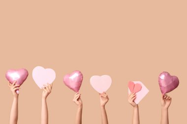 Hediye kutularıyla kadın elleri, kalp şeklinde hava balonları, zarf ve bej arka planda kağıt kalp. Sevgililer Günü kutlaması