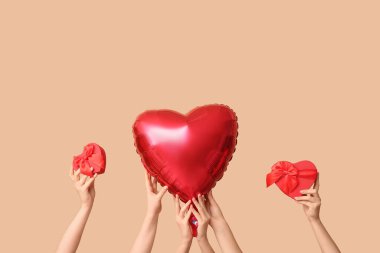 Hediye kutularıyla kadın elleri ve bej arka planda kalp şeklinde hava balonu. Sevgililer Günü kutlaması