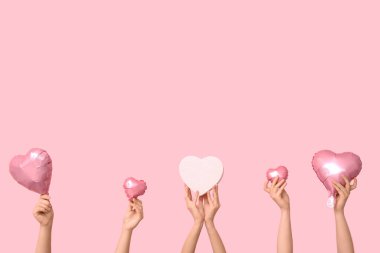 Hediye kutusu ve pembe arka planda kalp şeklinde hava balonları olan kadın elleri. Sevgililer Günü kutlaması
