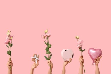 Hediye kutuları ve pembe arka planda çiçekleri olan kadın elleri. Sevgililer Günü kutlaması