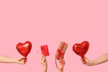 Hediye kutuları ve pembe arka planda kalp şeklinde hava balonları olan kadın elleri. Sevgililer Günü kutlaması