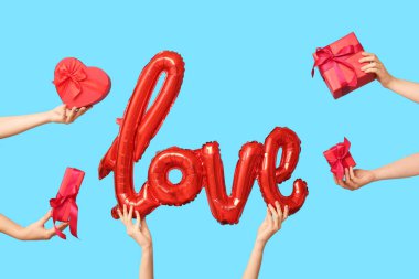 Balon şekilli kadın elleri ve mavi arka planda hediye kutuları. Sevgililer Günü kutlaması