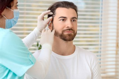 Klinikte saç büyütme iğnesi yaptıran yakışıklı adam.