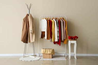 Paltolar ve süveterler ile raflar ışık duvarının yanında.