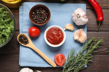 Bir kase taze domates ezmesi ve ahşap masada aromatik baharatlarla kompozisyon.