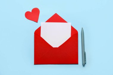 Kırmızı zarf, üzerinde boş kart, renkli kalem ve kağıt kalp var. Sevgililer Günü kutlaması