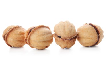 Beyaz arka planda kaynamış konsantre sütle pekçok tatlı ceviz şekilli kurabiye.