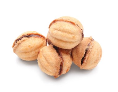 Beyaz arka planda kaynamış konsantre sütle pekçok tatlı ceviz şekilli kurabiye.