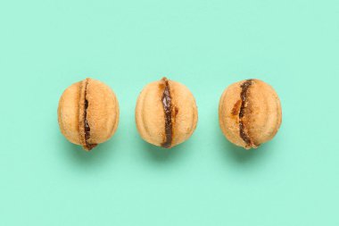 Turkuaz arka planda haşlanmış konsantre sütle ceviz şeklinde kurabiyeler.