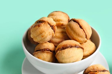 Turkuaz arka planda kaynamış konsantre sütle ceviz şeklinde kurabiyeler.