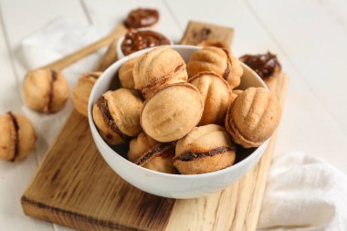 Beyaz ahşap arka planda kaynamış konsantre sütle ceviz şeklinde kurabiyeler.