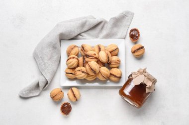 Beyaz arka planda kaynamış yoğunlaştırılmış sütle ceviz şeklinde kurabiyeler.