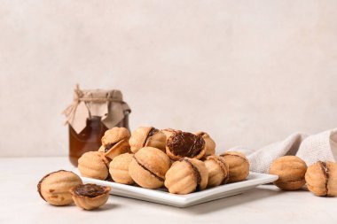 Beyaz arka planda kaynamış yoğunlaştırılmış sütle ceviz şeklinde kurabiyeler.