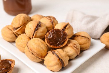 Beyaz arka planda kaynamış yoğunlaştırılmış sütle ceviz şeklinde kurabiyeler, yakın plan.